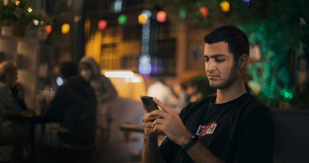 Turkish man in a dark shirt looking at his phone